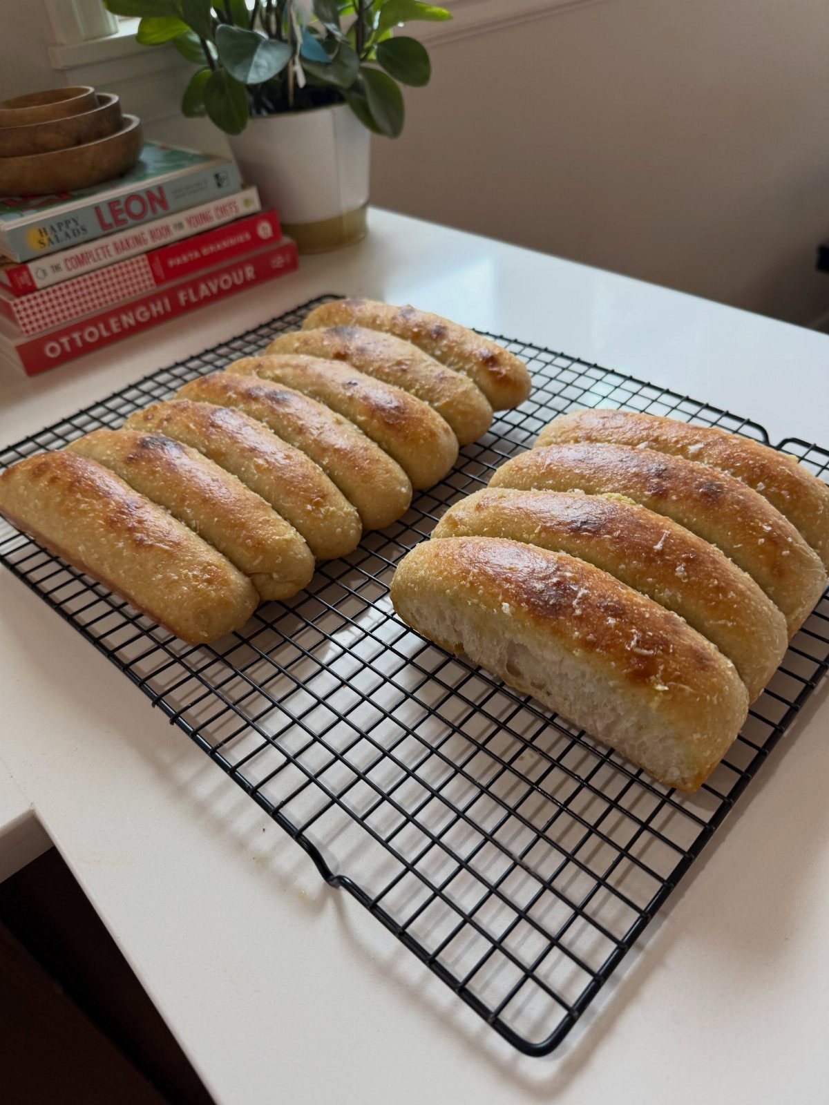 Golden brown breadsticks cooling on a black wire rack on a white counter.